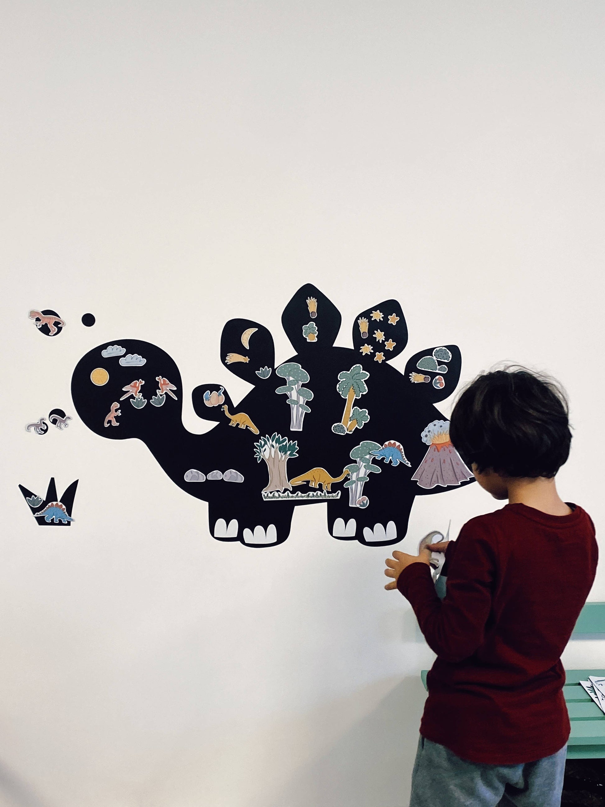 Copil care se joacă cu joc magnetic cu dinozauri pe tablă magnetică.